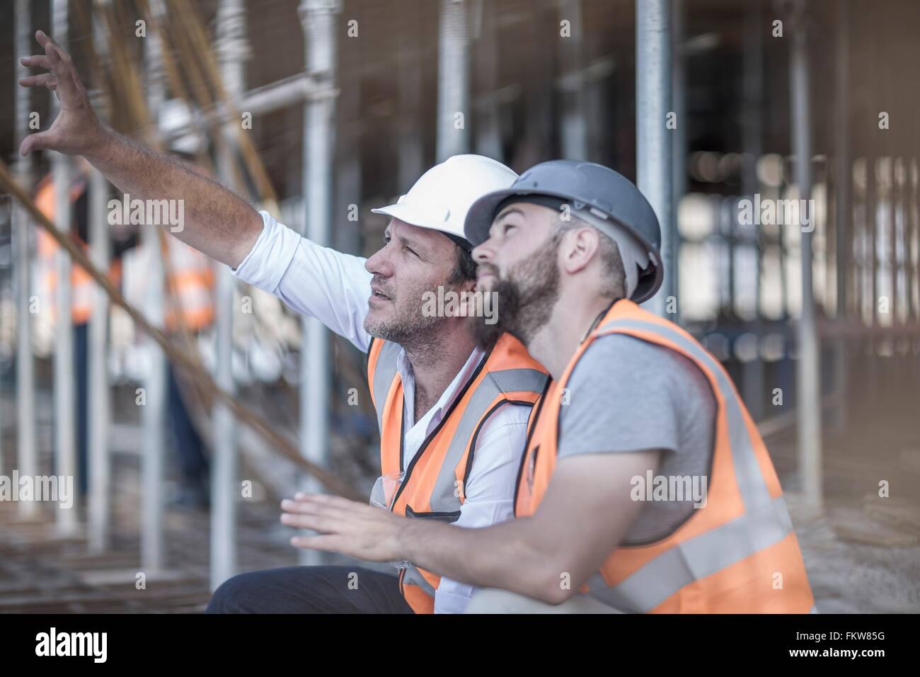 Site manager and builder looking up at steel rods on construction site