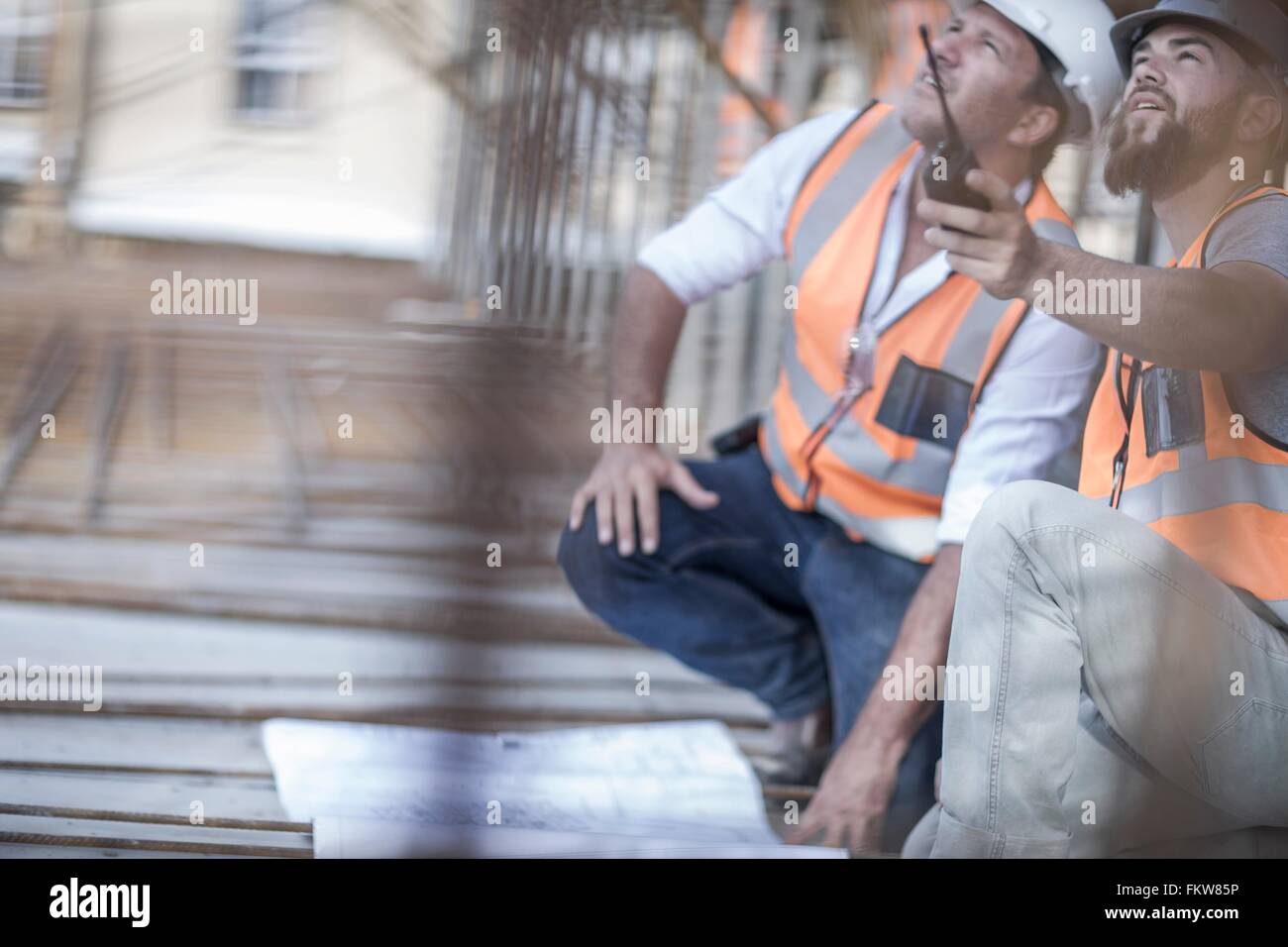 Point Up Construction Site manager and builder pointing up from blueprint on construction ...