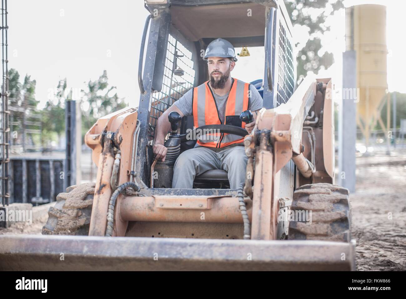 Builder driving excavator on construction site Stock Photo