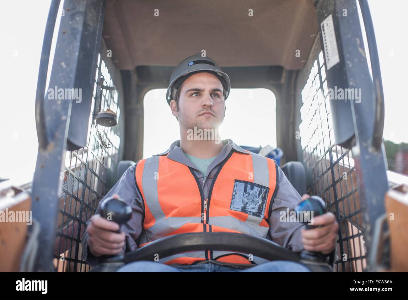 Young man driving excavator on construction site Stock Photo