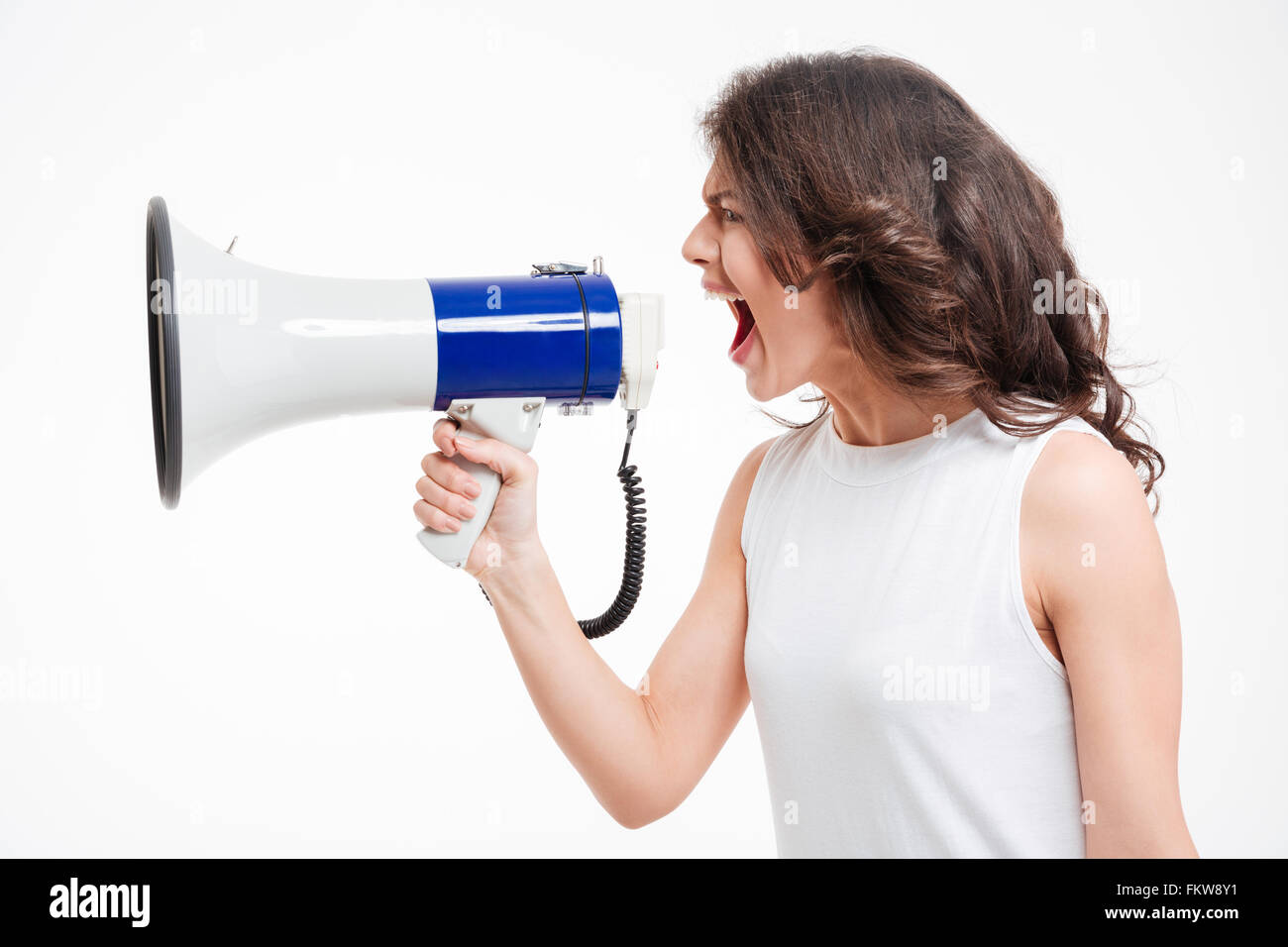 Side view portrait of a young woman screaming into megaphone isolated on a white background Stock Photo