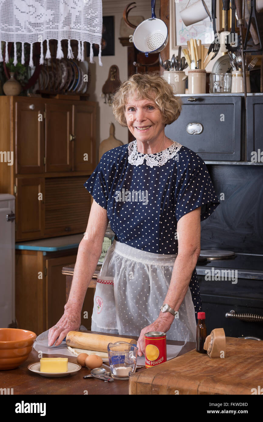 A happy grandmother making a pie in clothing and kitchen in the 1940's