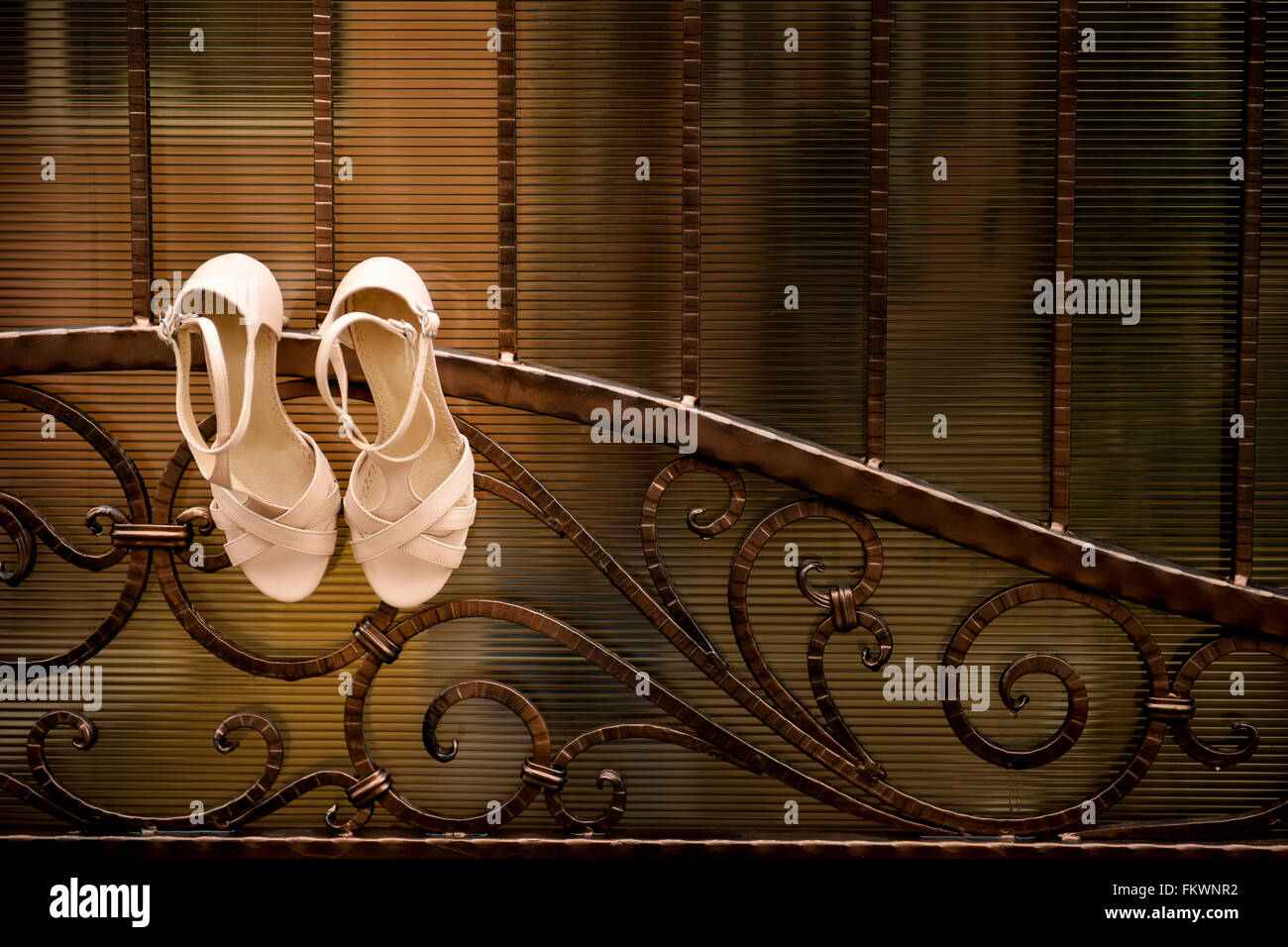 White wedding shoes hang a wrought iron fence Stock Photo