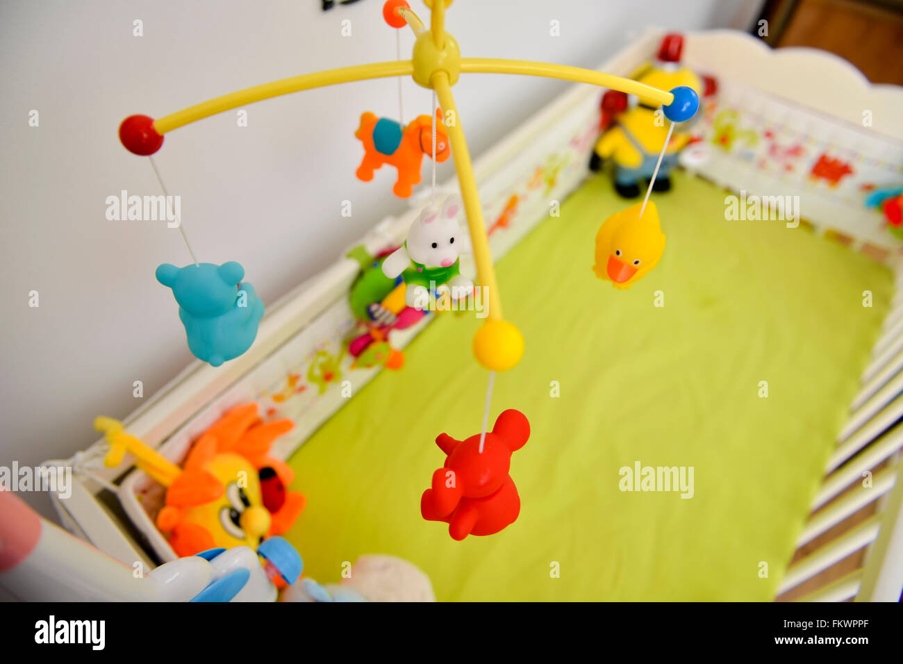 Baby cot with colorful toys hanging Stock Photo