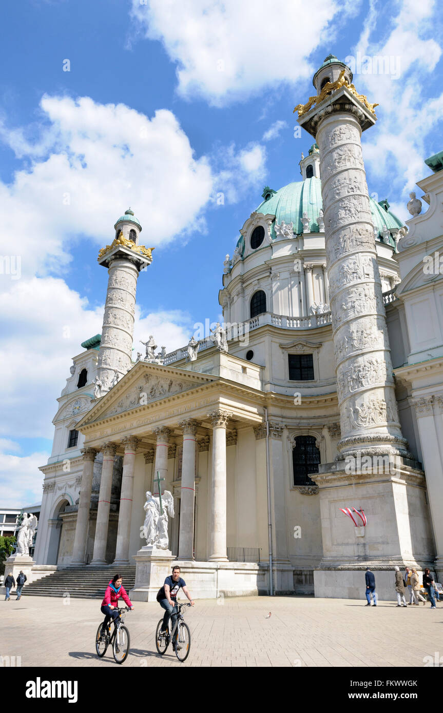 Two cyclists ride in front of the Karlskirche (St Charles's church), Karlplatz, Vienna, Austria Stock Photo