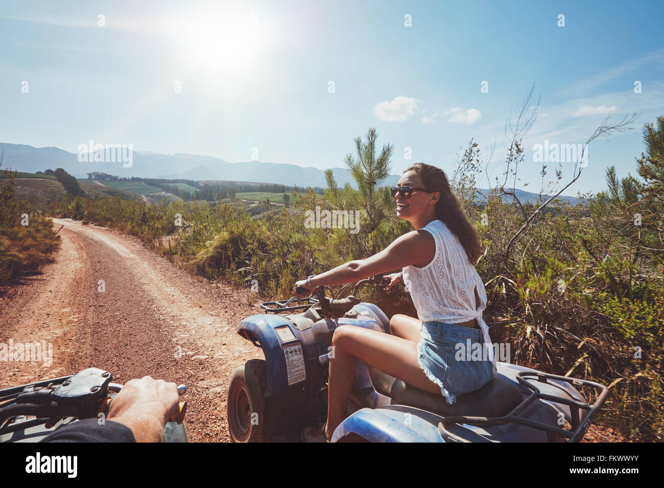 Young woman on quad bike on a trail. Young woman driving all terrain vehicle in nature on a sunny day. Stock Photo