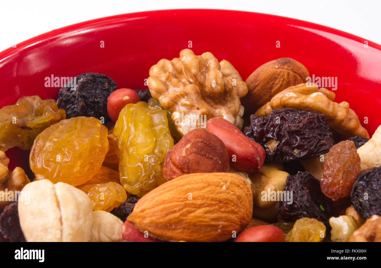 various different mixed nuts and raisins in red plate on white