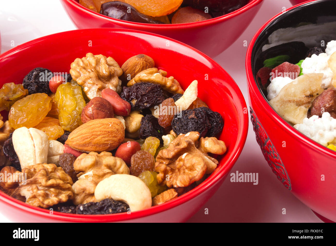 various different mixed nuts and raisins in red plate on white