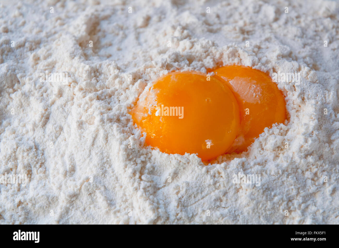 Two egg yolks on flour. Close view. Stock Photo