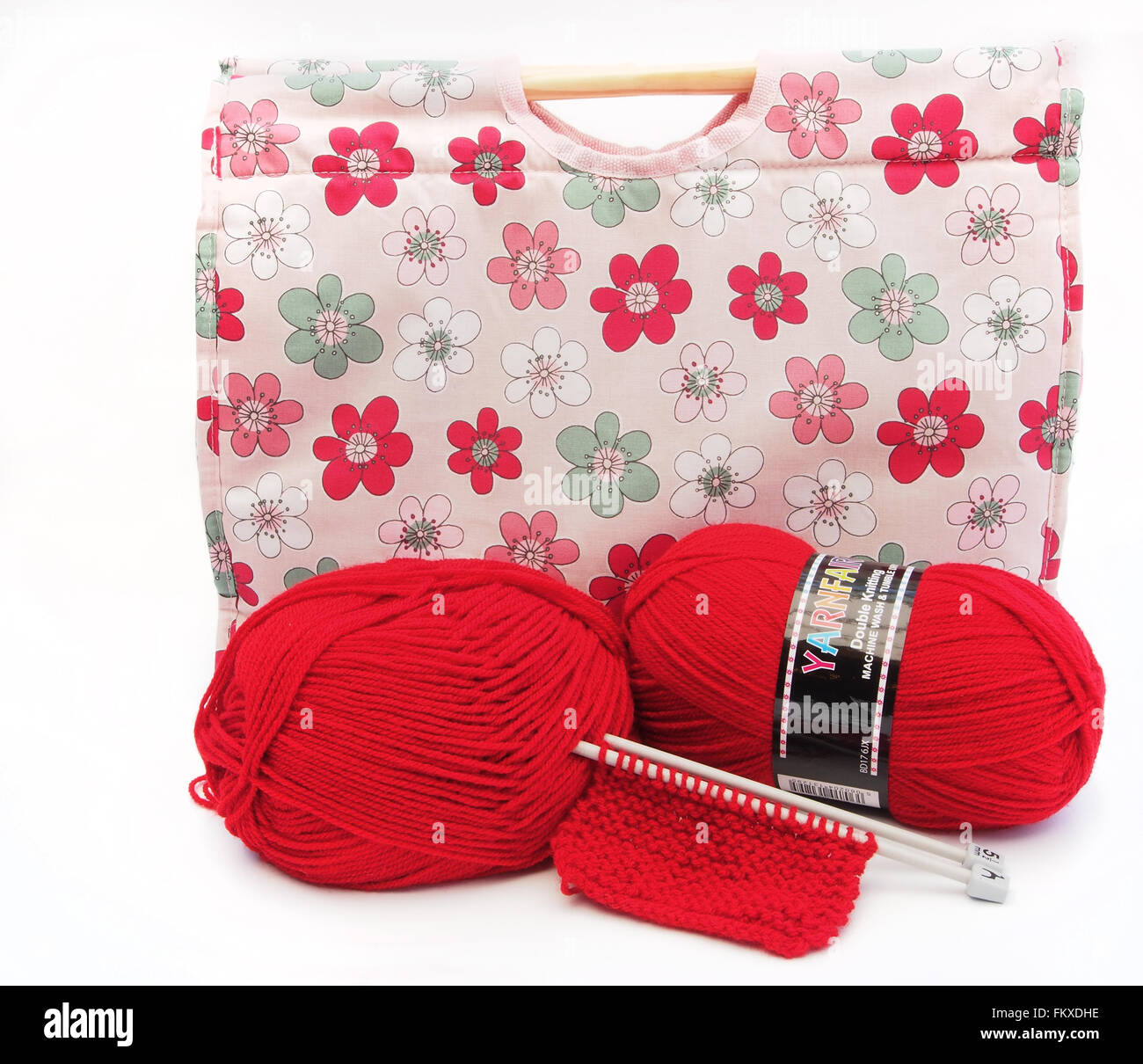 Pink flower patterned knitting / craft bag with knitting needles, knitting and two red balls of wool. Stock Photo
