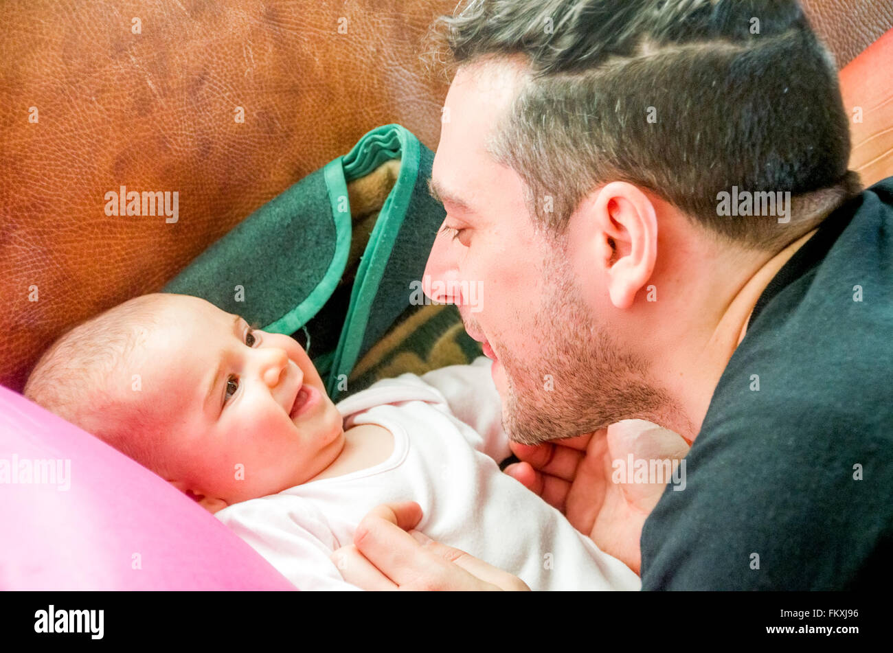 Dad makes faces grimacing newborn baby laughs Stock Photo