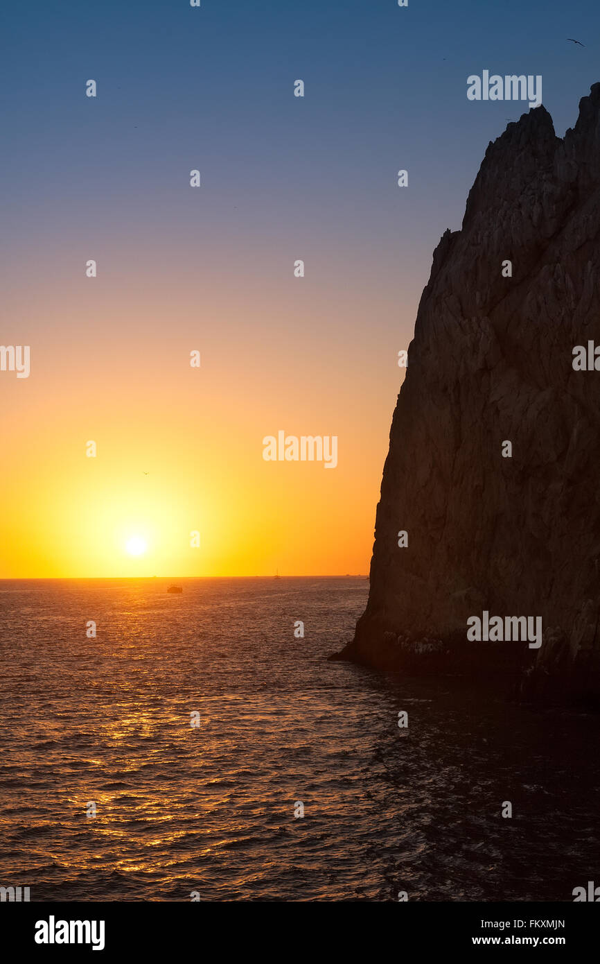 Sun setting on the horizon in Cabo San Lucas at the natural rock formation, Land's End. Stock Photo