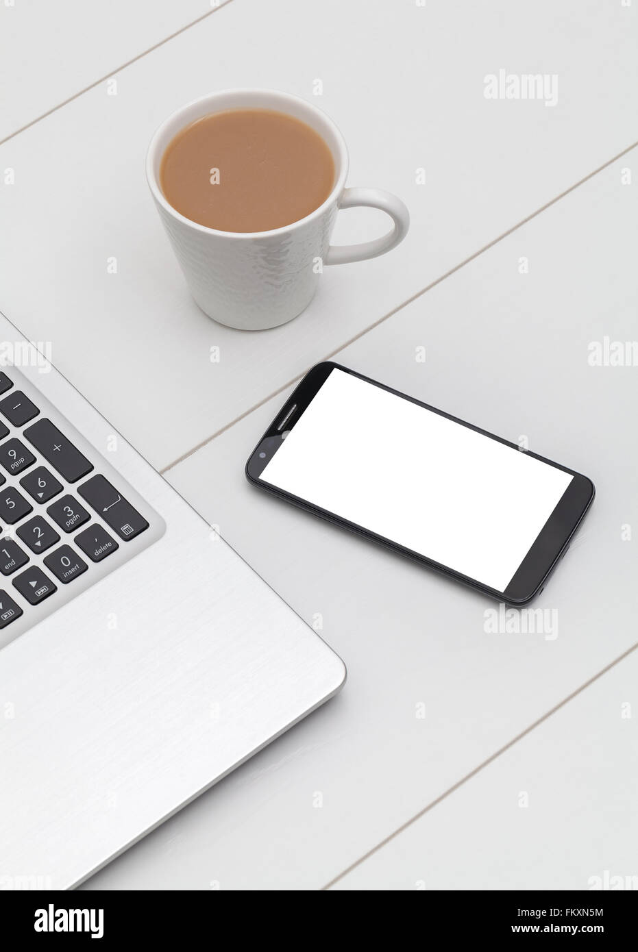 smartphone mockup, laptop and coffee on office table Stock Photo