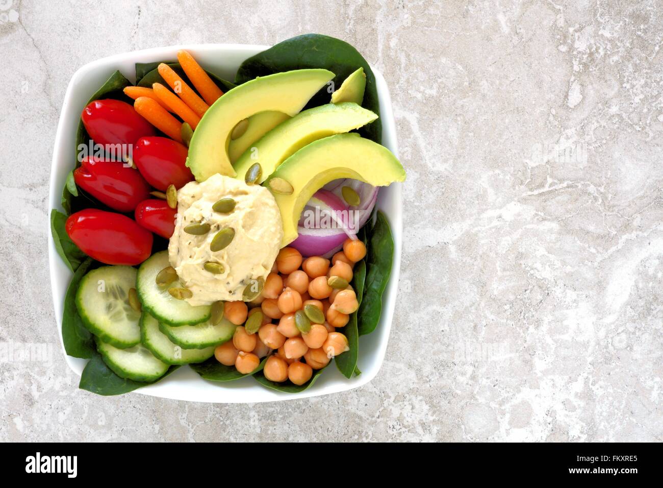 Healthy lunch bowl with fresh vegetables and hummus, overhead view on white marble Stock Photo