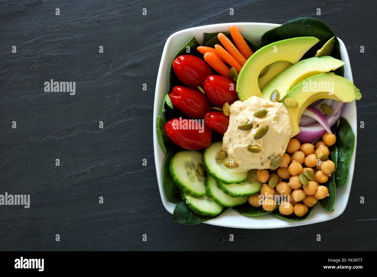 Healthy nourishment bowl with super-foods and fresh mixed vegetables, overhead view on dark slate Stock Photo