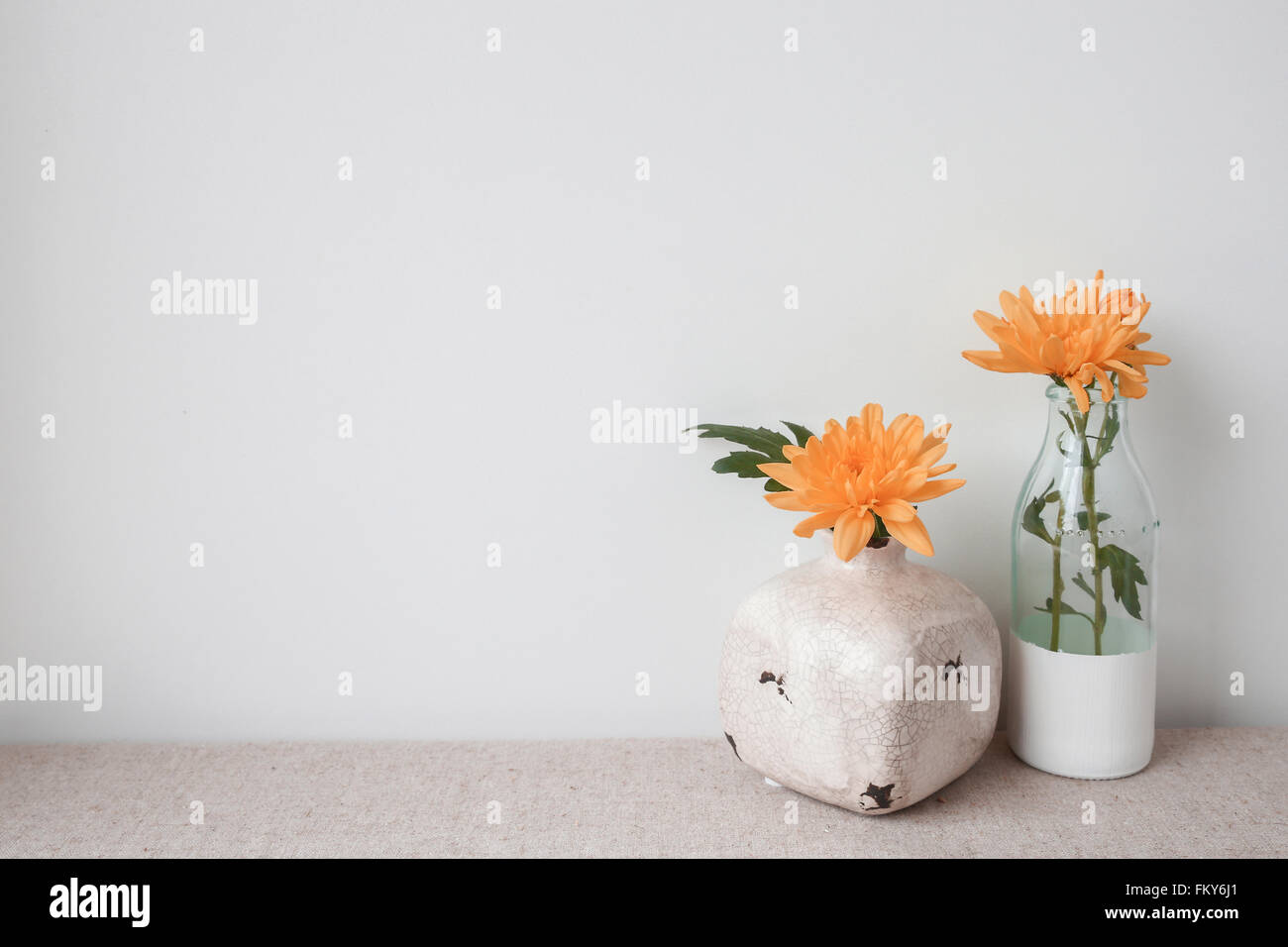 Orange flowers in pot and glass bottle, home decoration Stock Photo