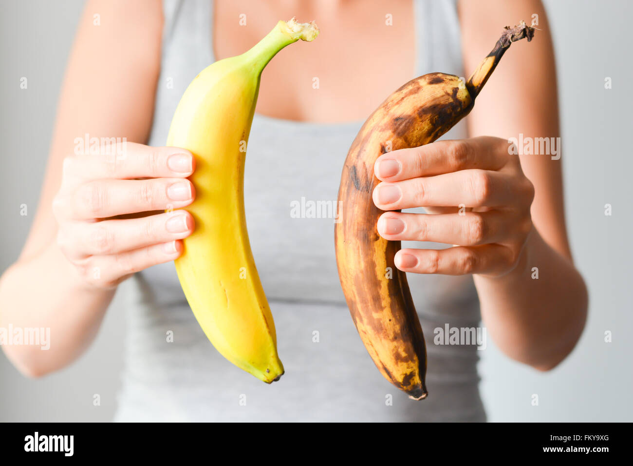 Fresh and overripe bananas on woman hand Stock Photo