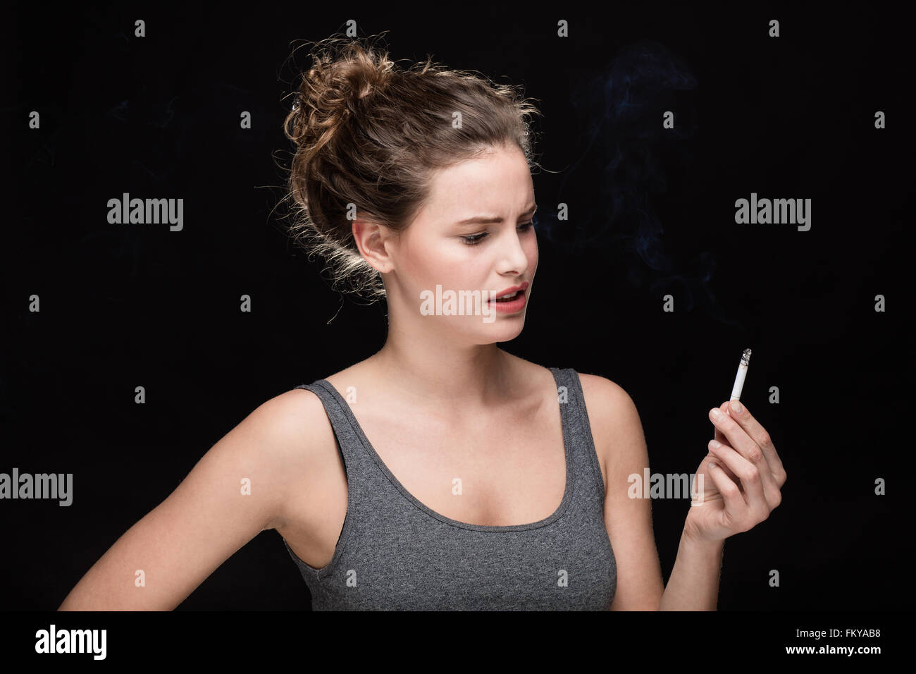 young woman with cigarette, smoking concept on black background Stock Photo
