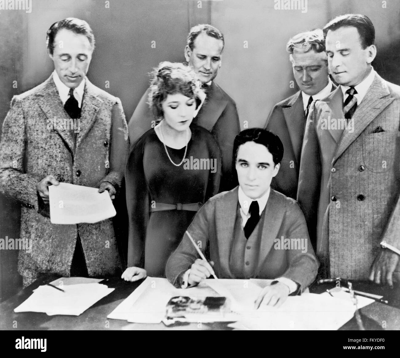 D.W. Griffith, Mary Pickford, Charlie Chaplin (seated) and Douglas Fairbanks at the signing of the contract establishing United Artists motion picture studio in 1919. Two lawyers, Albert Banzhaf (left) and Dennis F. O'Brien, are standing in the background. Stock Photo