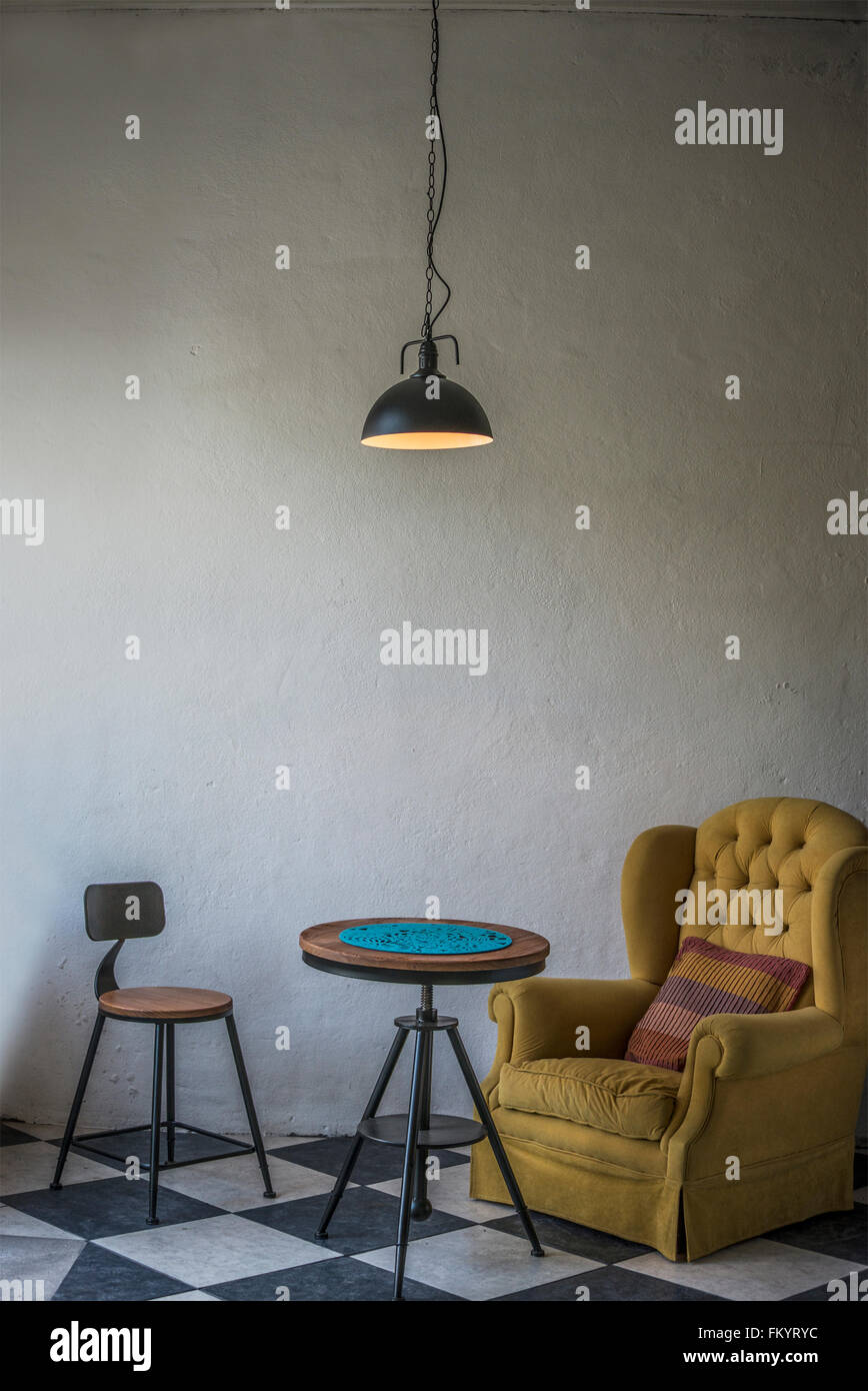 Vintage hipster loft interior with yellow armchair and an iron stool Stock Photo