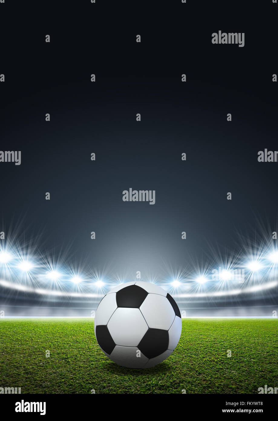 A generic stadium with an unmarked green grass pitch at night under illuminated floodlights and a regular soccer ball Stock Photo