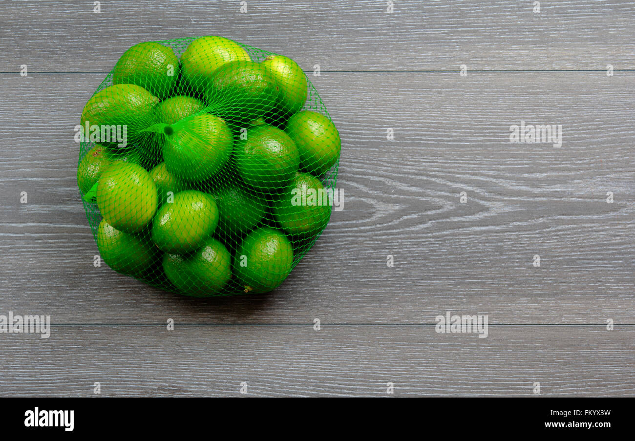 Limes in a bag on wood board background Stock Photo