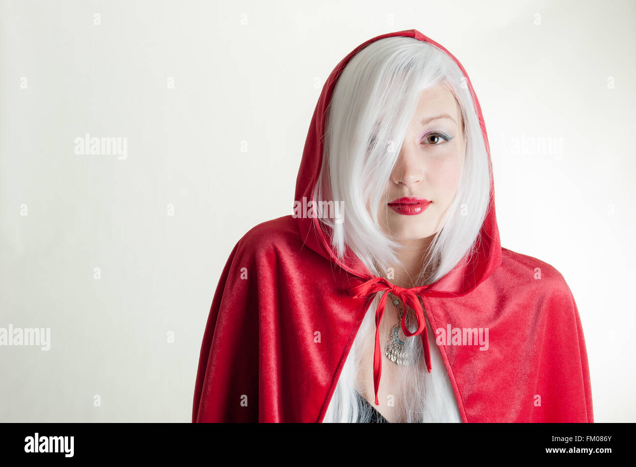 young lady in red hooded cape and wolf shadow on wall Stock Photo