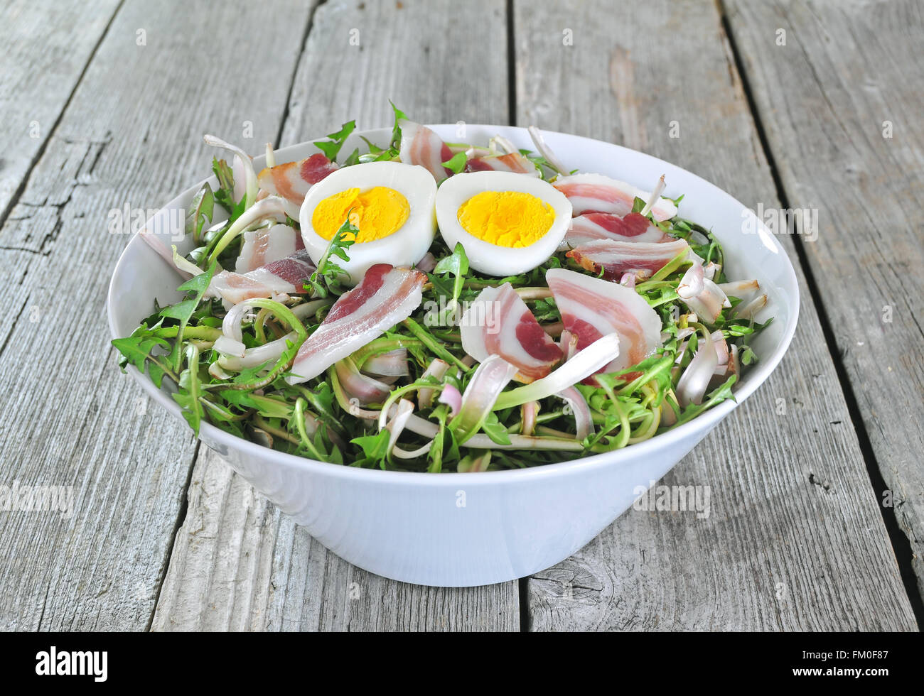 Fresh dandelion salad with boiled eggs and bacon Stock Photo