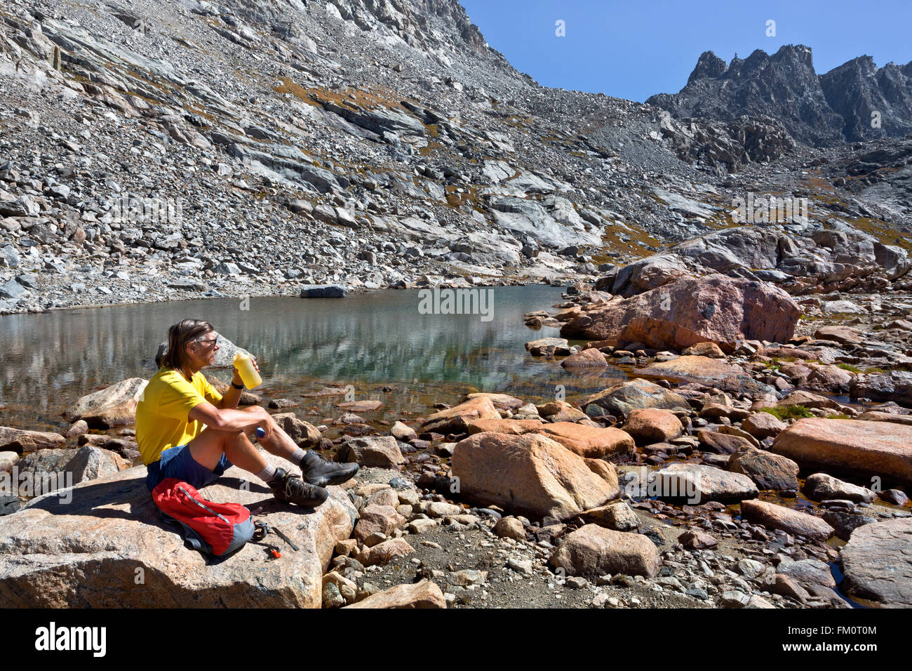 WY01275-00...WYOMING - Hiker taking a break below Indian Pass in the Wind River Range. Stock Photo