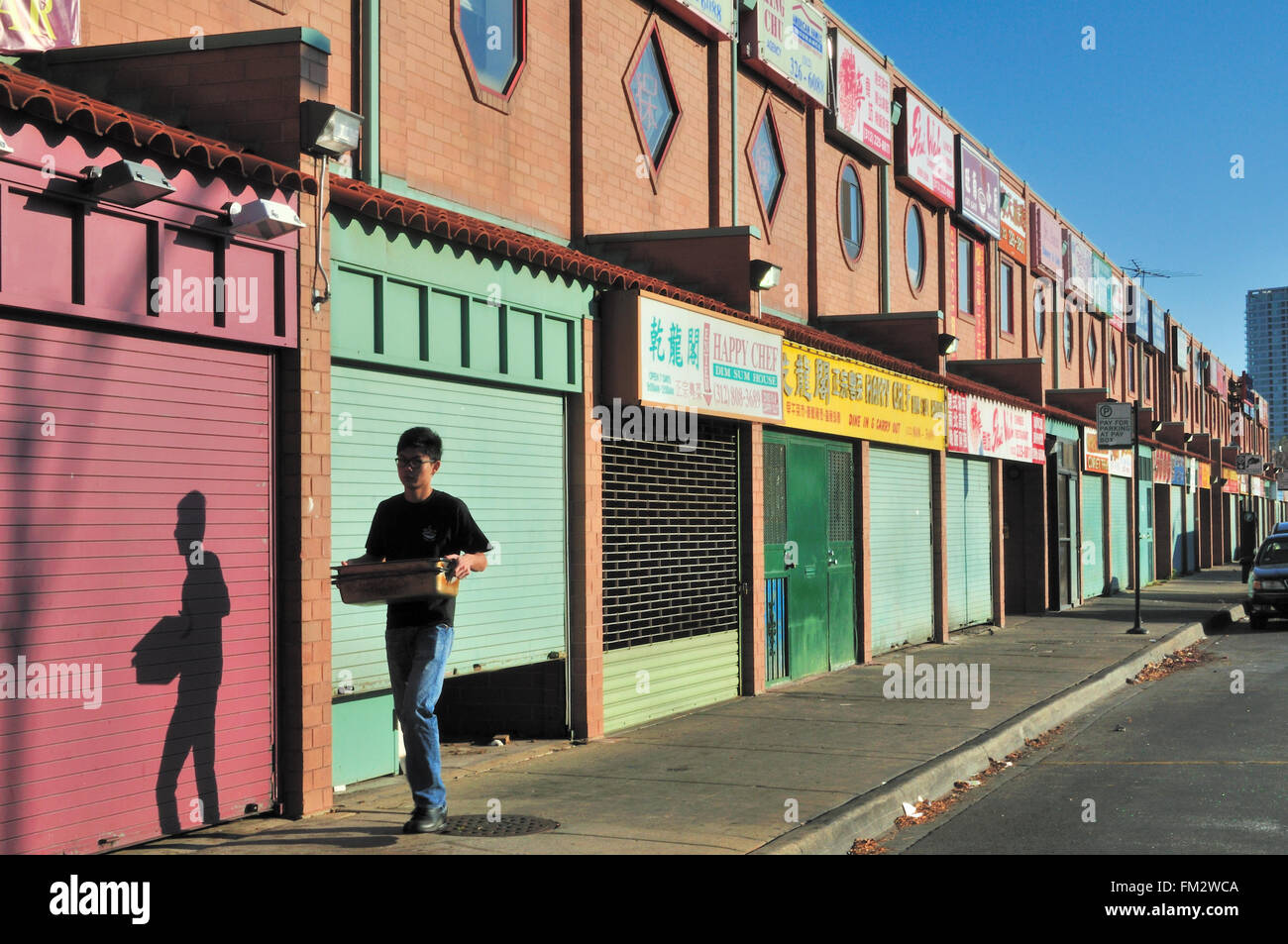 Stalls in Chicago's Chinatown reflect the early light of day as an isolated man goes about his work before the stores open. Chicago, Illinois, USA. Stock Photo