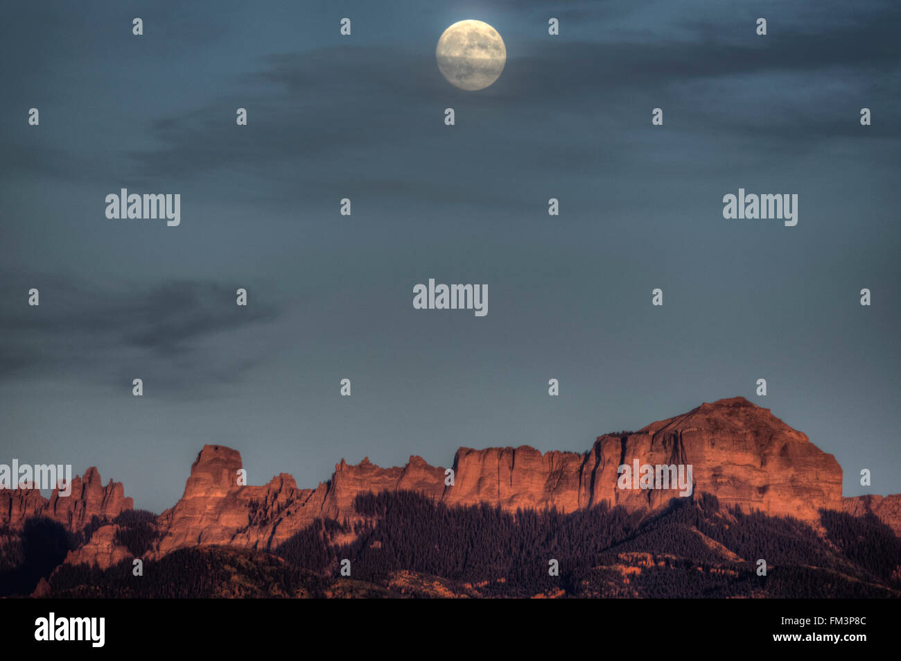 The moon rises over two local landmarks of Ridgeway, Colorado:  Chimney Rock on the left, and Courthouse Mountain on the right. Stock Photo