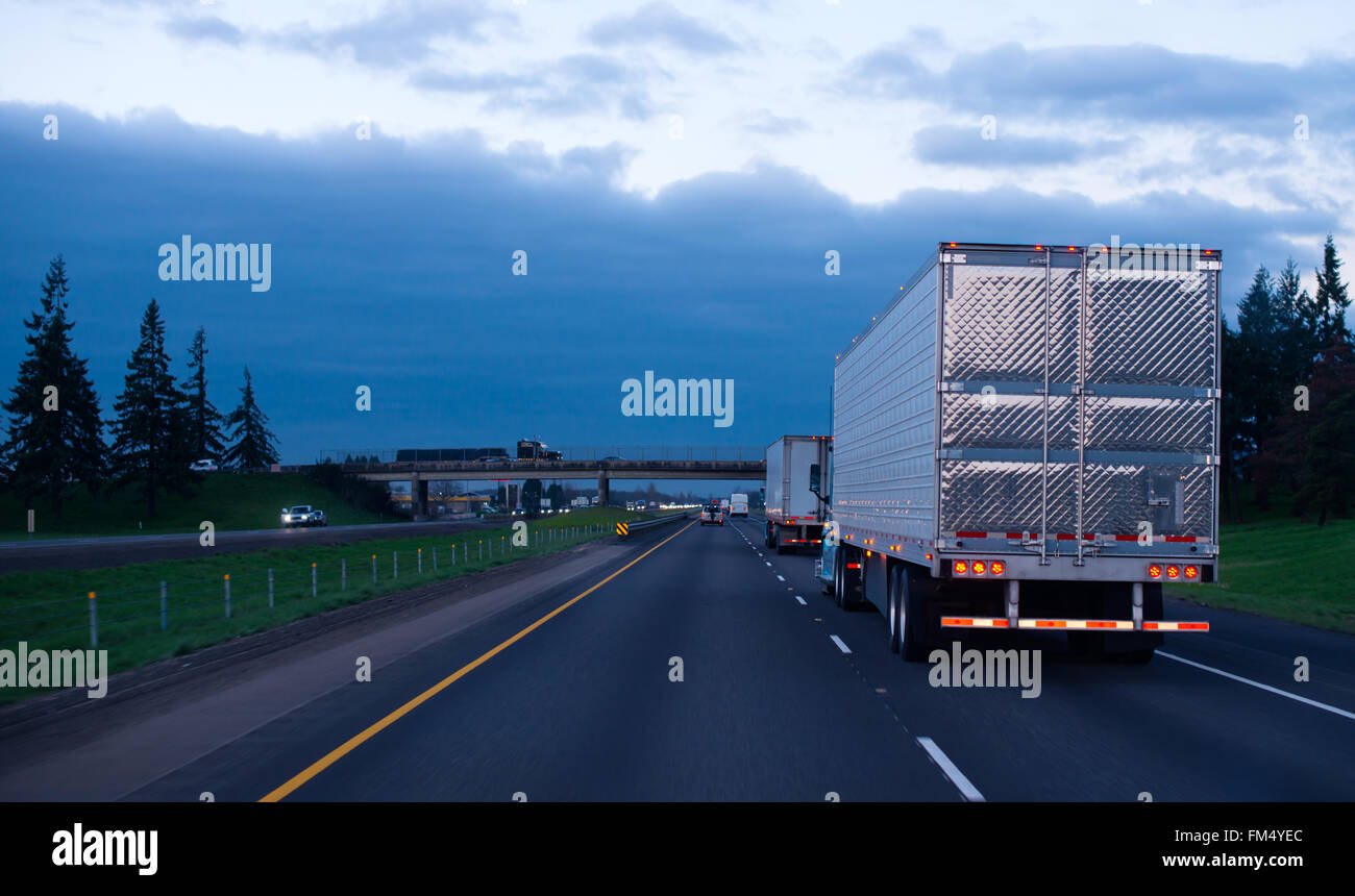The convoy of semi trucks with reefer trailers on flat like an arrow