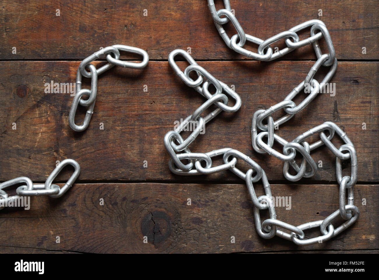 Unlinked metal chain on nice old wooden background Stock Photo