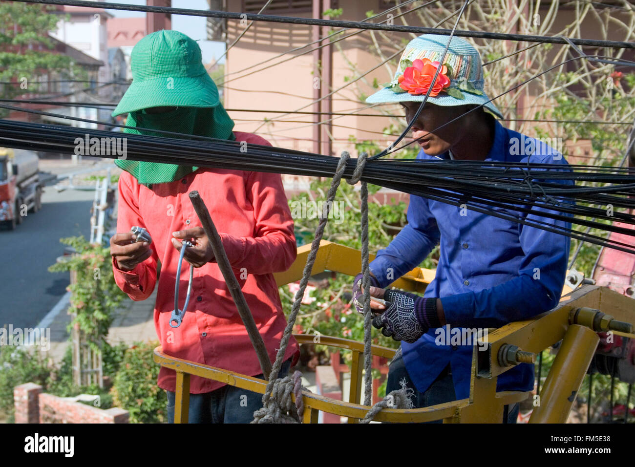 Two men are working on power and telephone lines in Kampong Cham