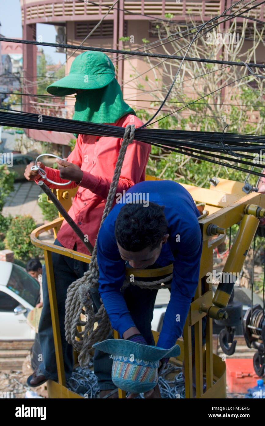 Two men are working on power and telephone lines in Kampong Cham