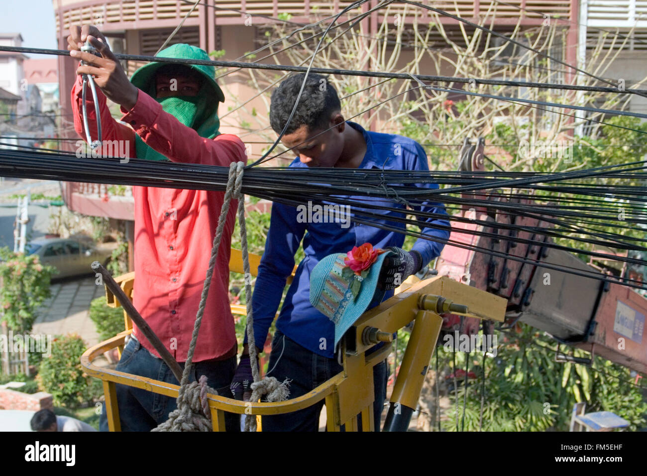Two men are working on power and telephone lines in Kampong Cham