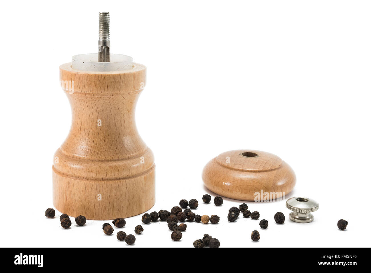 small pepper mill of wood standing in pepper corns with the lid of ready to be filled with new fresh pepper corns Stock Photo