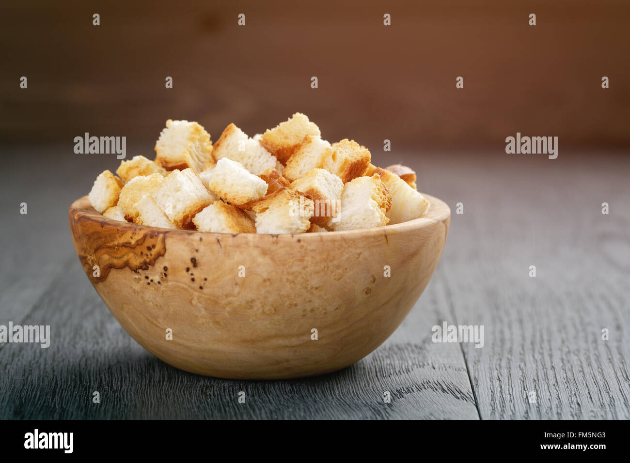 homemade croutons from white bread in wood bowl on oak table Stock