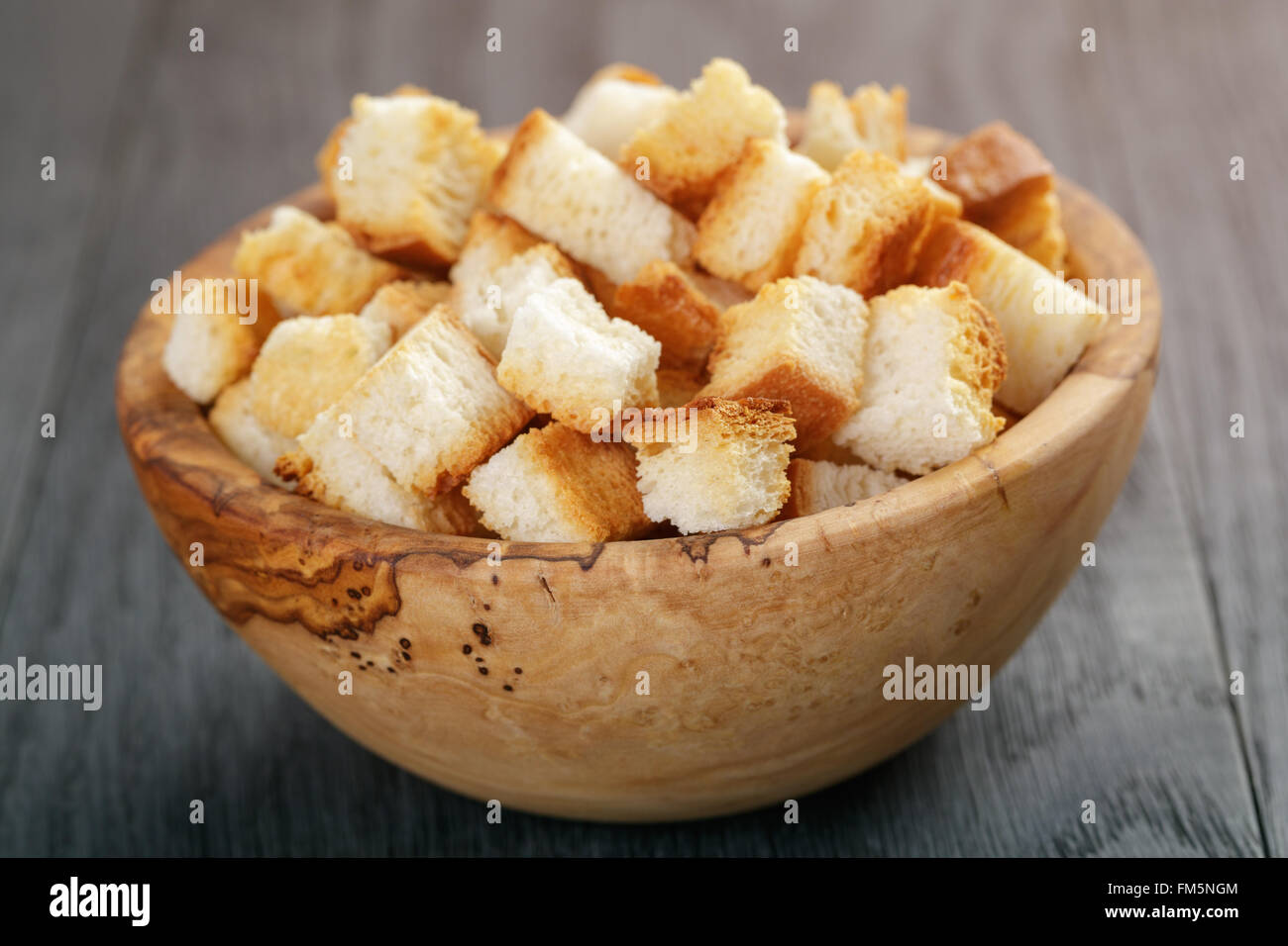 homemade croutons from white bread in wood bowl on oak table Stock