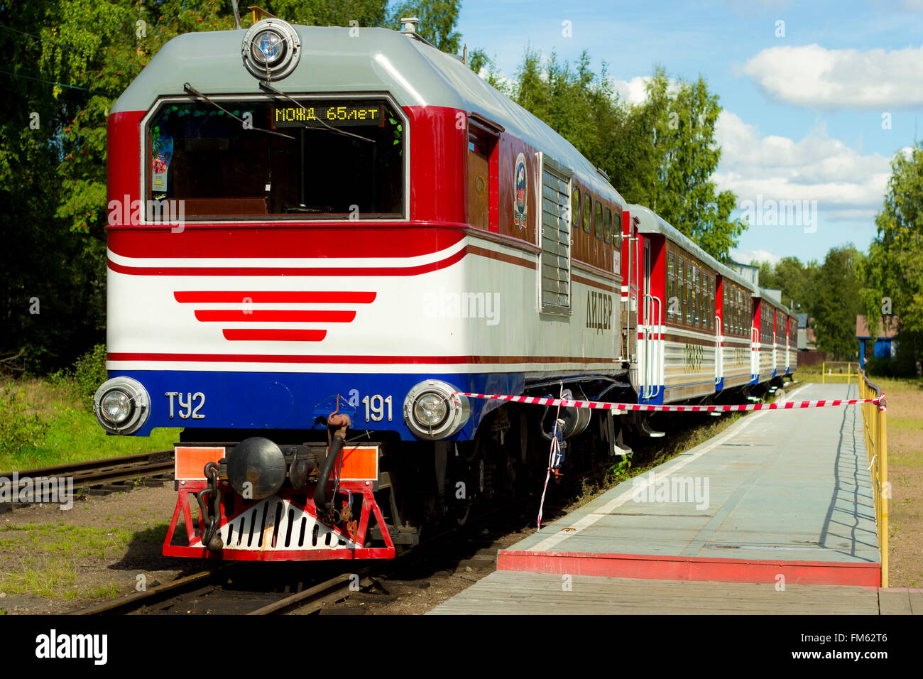 SAINT-PETERSBURG, RUSSIA - SEPTEMBER 4, 2013: Red-white locomotive with trailer cars passenger stands on a platform in forest Stock Photo