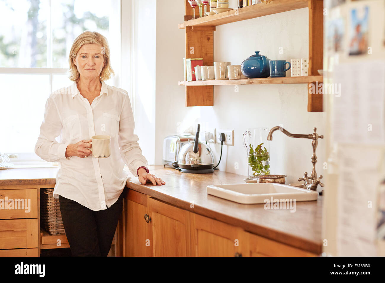 Worried looking senior woman standing in her kitchen Stock Photo