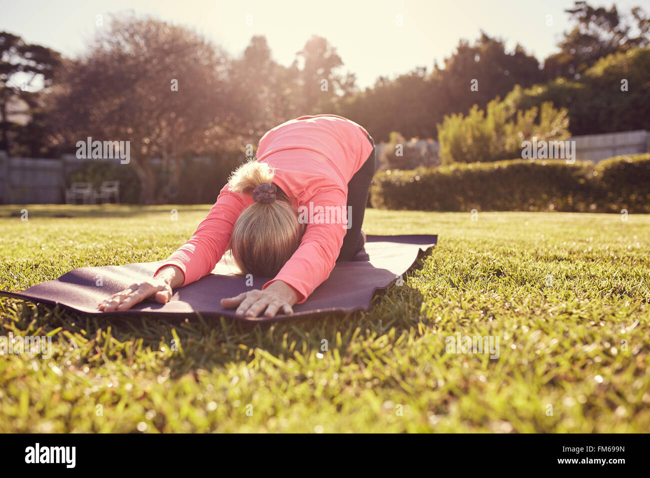 Senior woman doing yoga outdoors in gentle morning sunlight Stock Photo