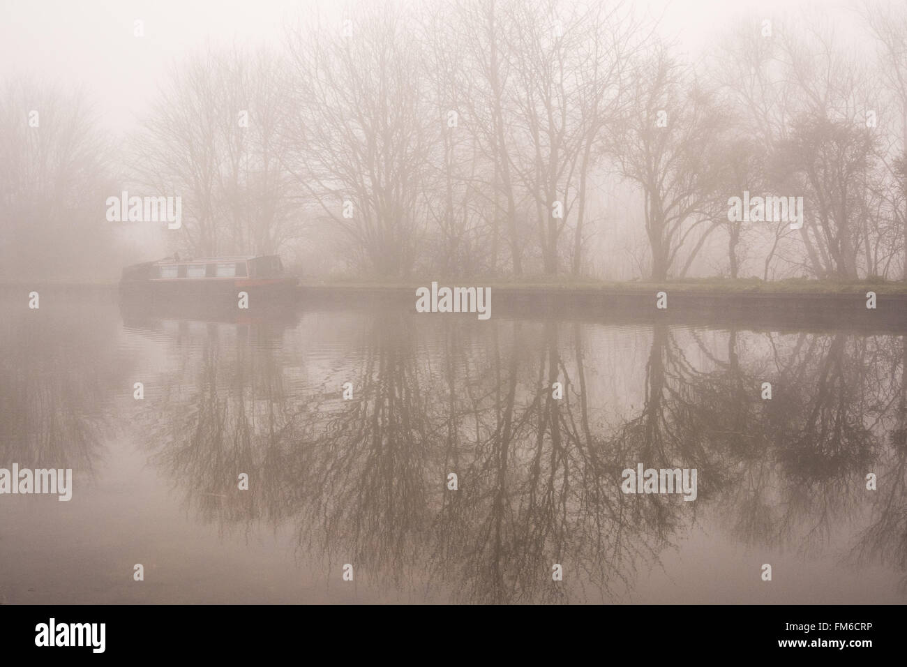 A houseboat and winter trees are mirrored in the still surface of the River Lee navigation in Tottenham, London on a foggy day.  Credit: Patricia Phillips/Alamy Live News Stock Photo