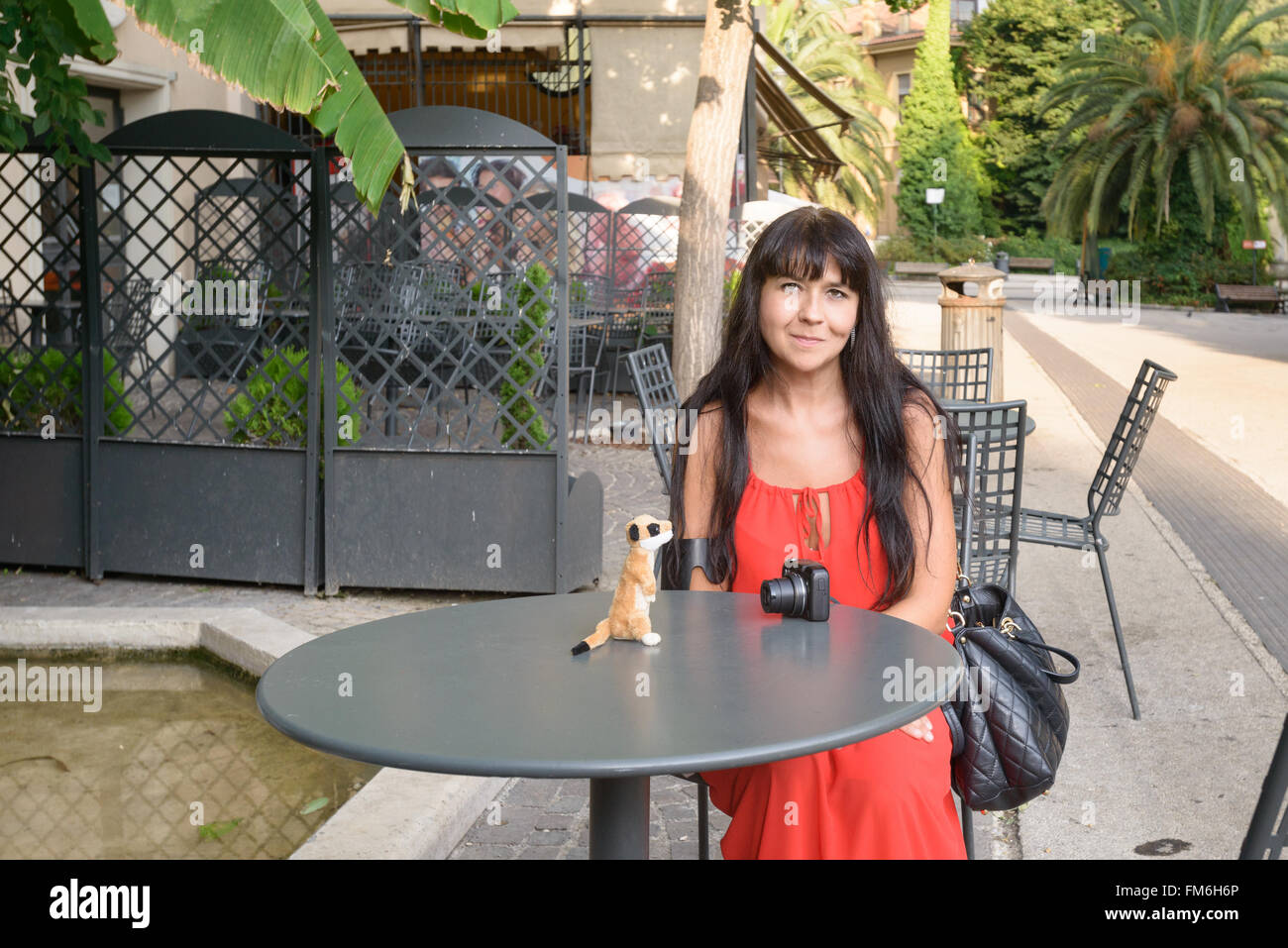 nice girl sitting on a chair at a little iron table with a puppet on it Stock Photo