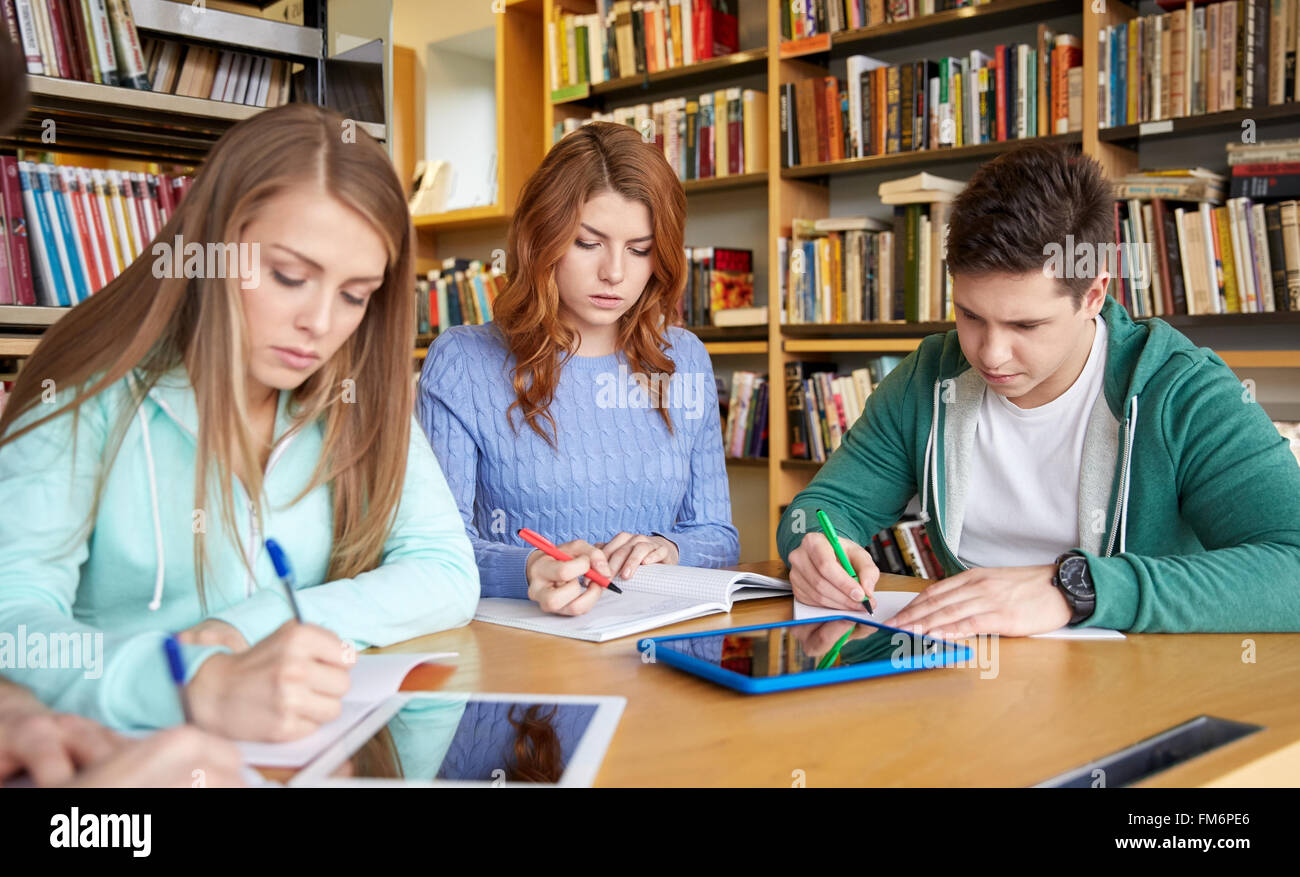 happy students writing to notebooks in library Stock Photo