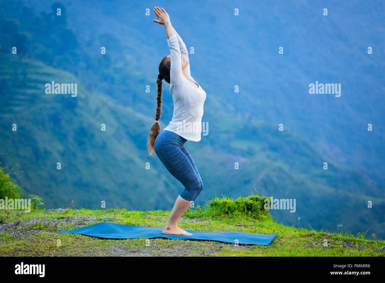 Woman doing yoga asana Utkatasana outdoors Stock Photo