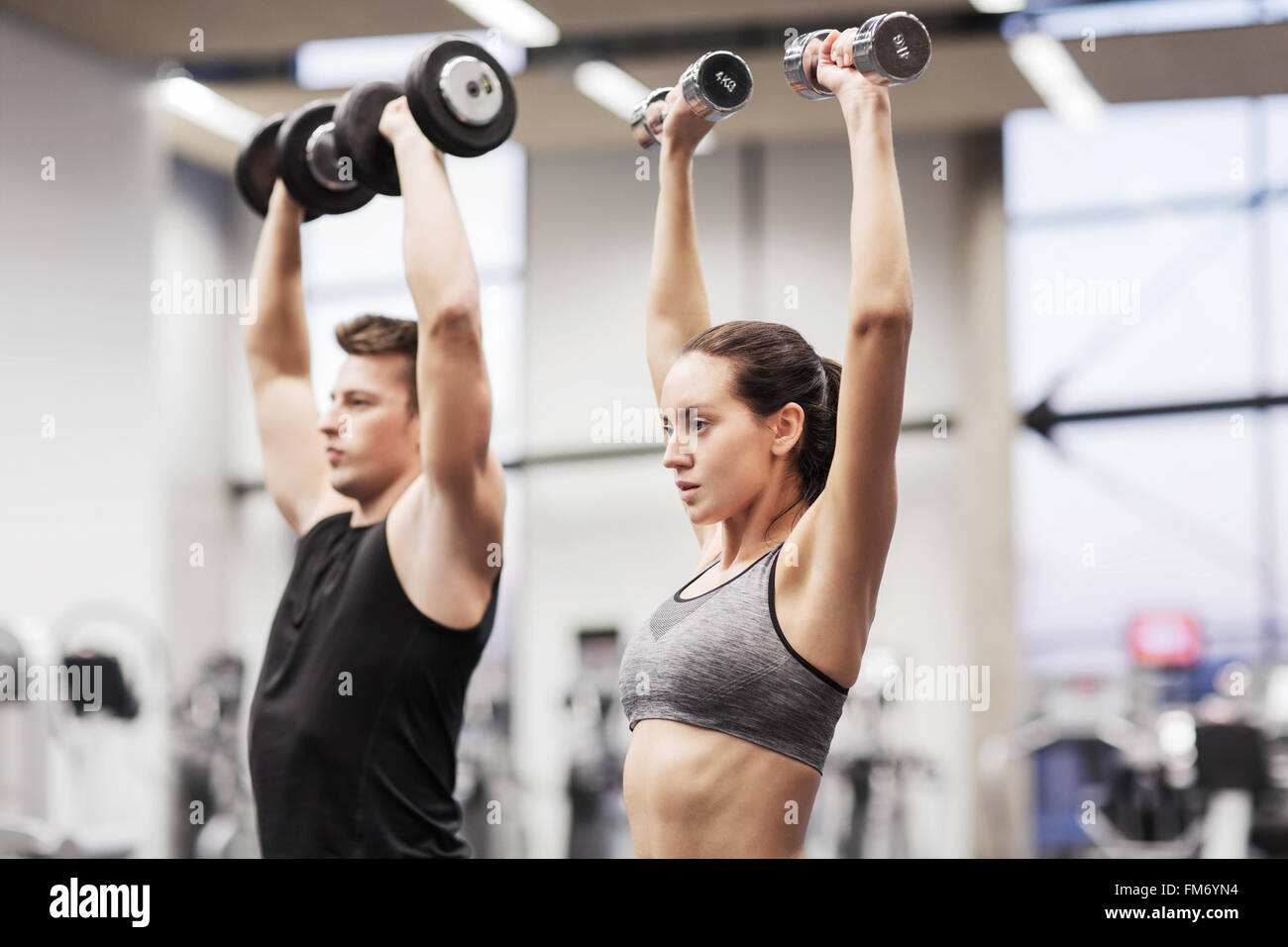 smiling man and woman with dumbbells in gym Stock Photo - Alamy
