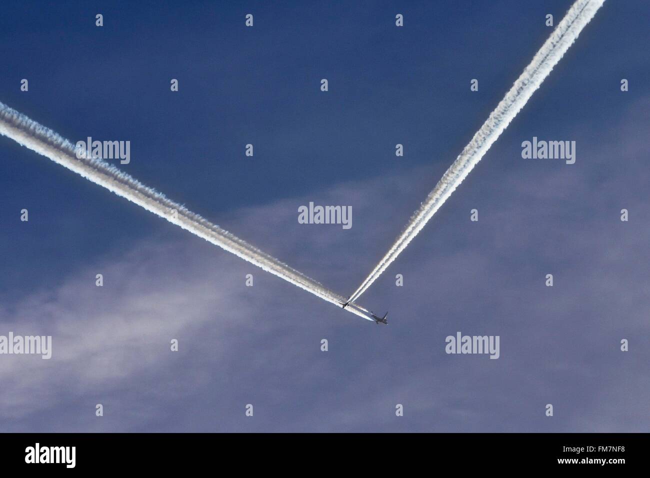 Aircraft long letter in full flight crossing a short distance, steam condensation trail Stock Photo