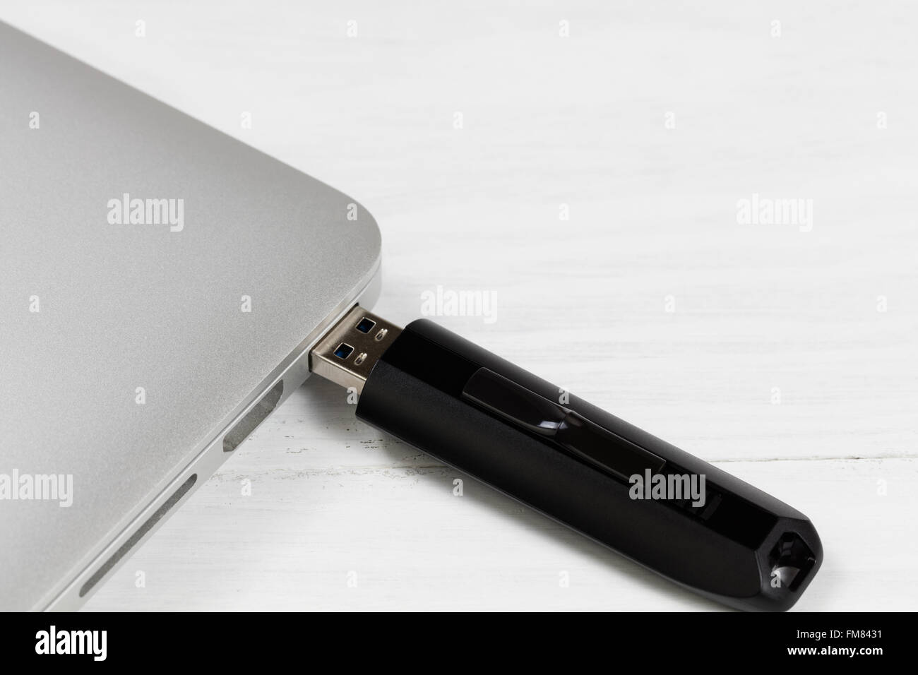 Portable thumb drive plugged into laptop computer USB slot. Selective focus on front part of drive. Stock Photo