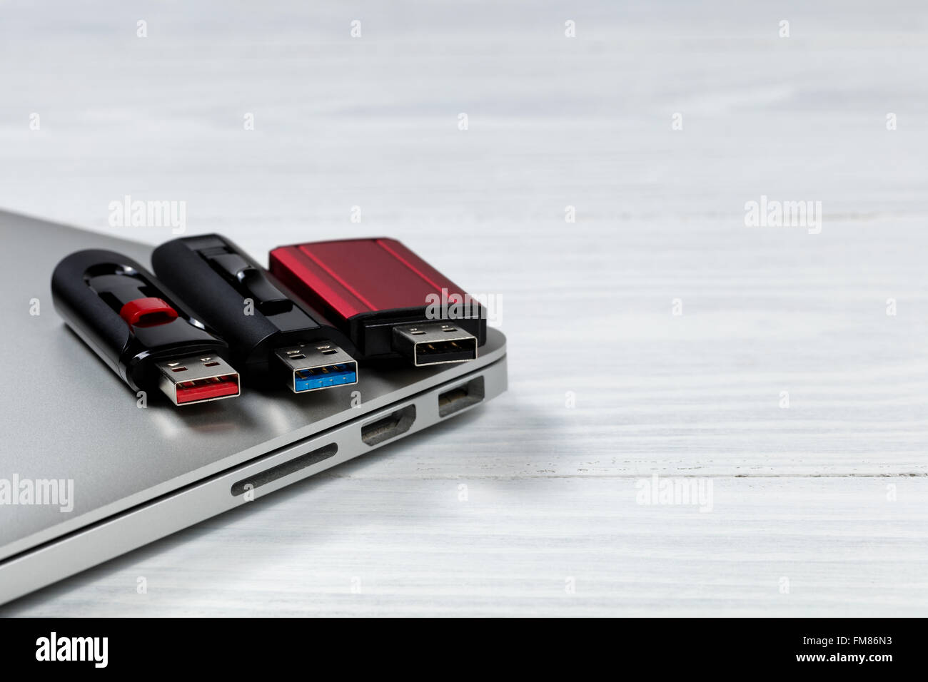 Three thumb drives with different colors inside for USB technologies. Computer and desktop in background. Stock Photo